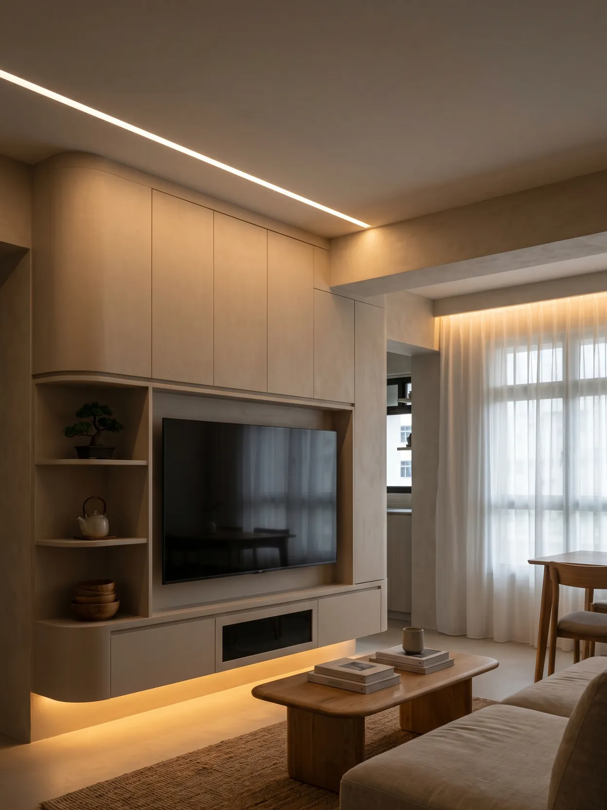 Open-plan living and dining room of a completed HDB flat, with a full-height built-in wall around the television, open shelving and a dining table by the window